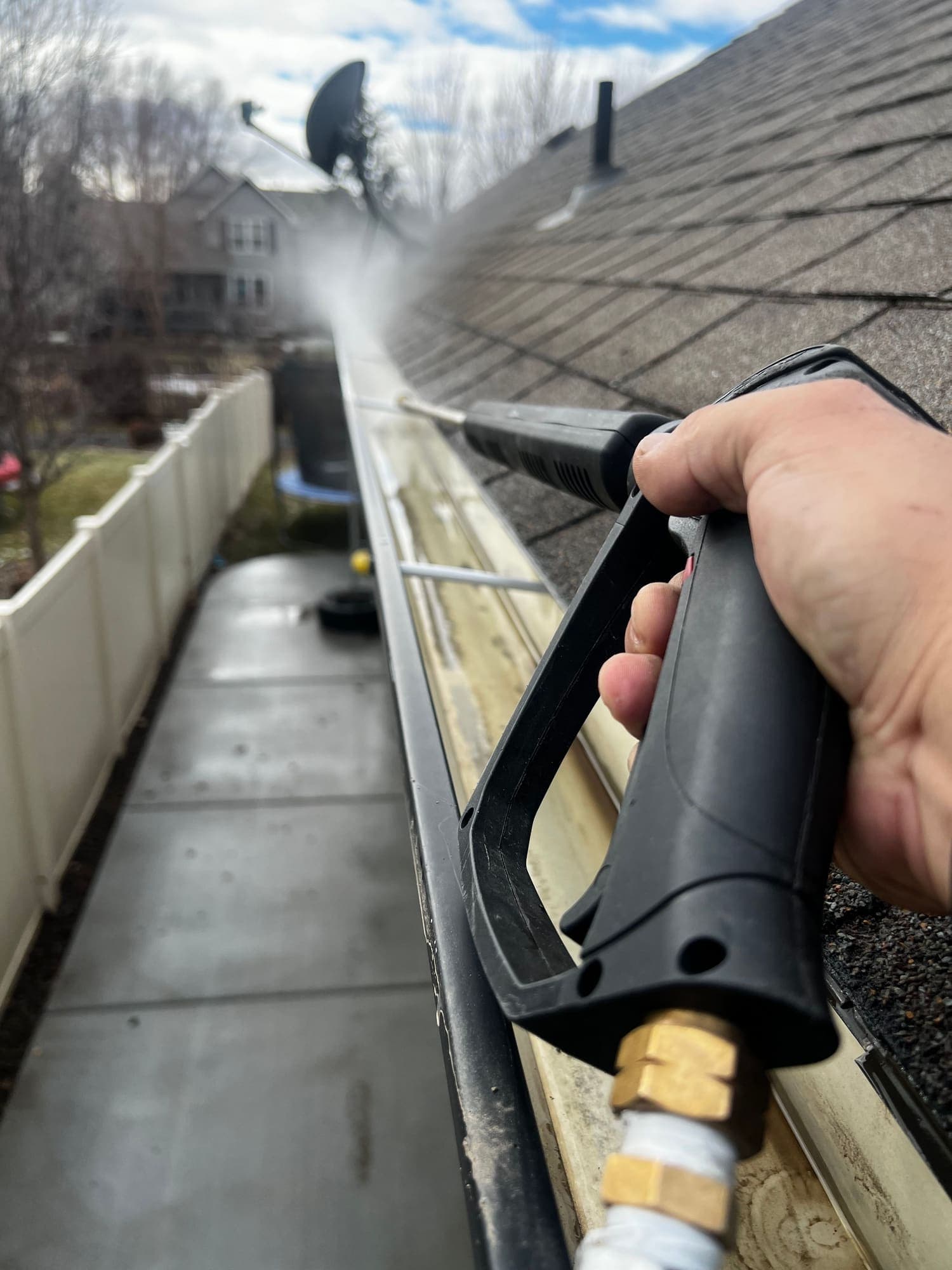 Gutter being cleared of built-up debris on a house roofline