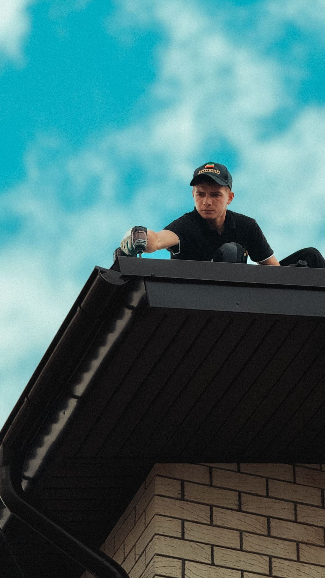 Worker up on a house roof against a clear sky