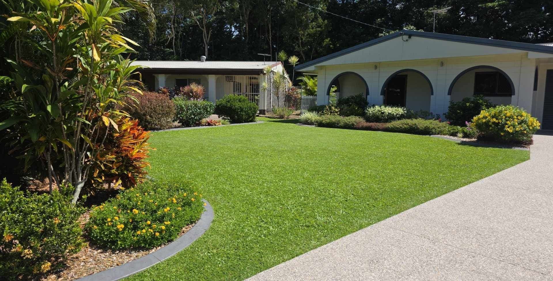 Edged garden beds with established planting beside a mown lawn at a Cairns home