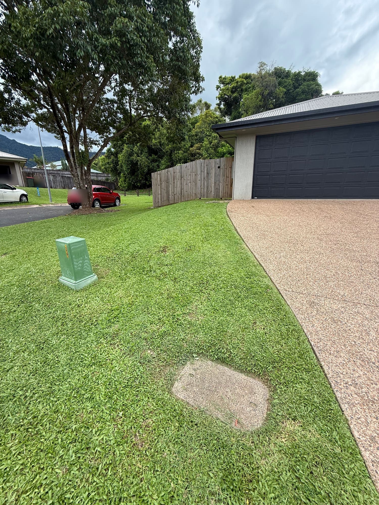 Mown front lawn and driveway at a Cairns home, with the ranges behind