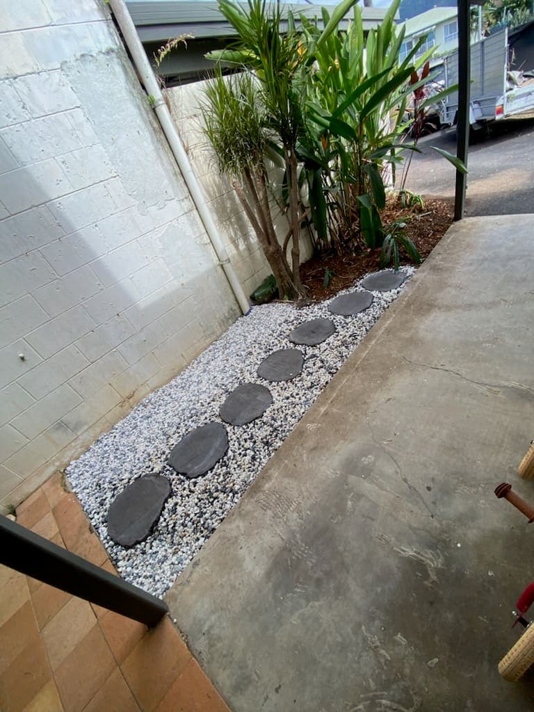 Stepping stones set through pebble along a side path beside a planted bed