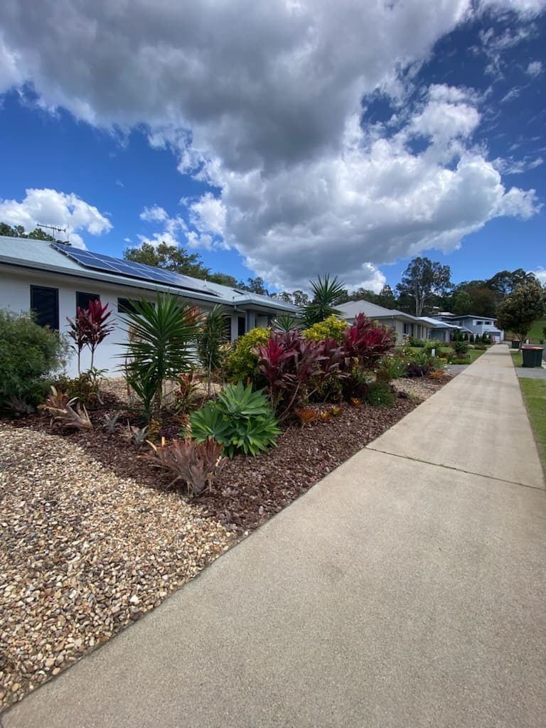 Maintained garden strip and mulched beds running along a row of units